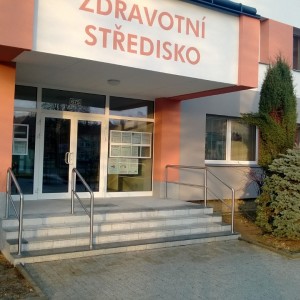 Krátké pomocné zábradlí u malého schodiště před zdravotní budovou