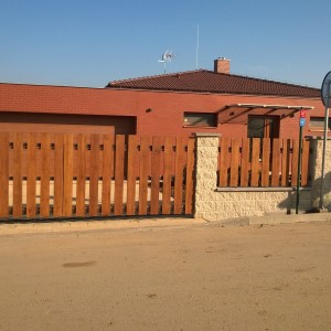 Plot a vjezdová brána s dřevěnými plotovkami u rodinného domu