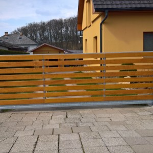Posuvná vjezdová brána u rodinného domu s podélnými dřevěnými plotovkami